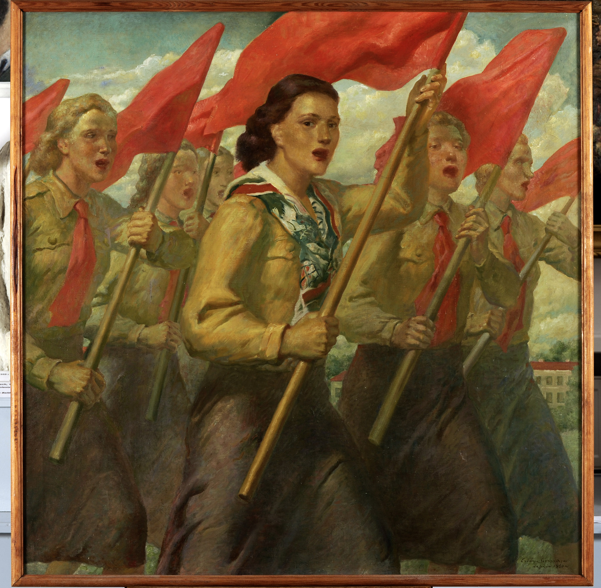 Ludomir Śledziński, „Wolny śpiew”, 1950, olej, płótno, nr inw. MPK/SW/124 Obraz namalowany farbami olejnymi na płótnie z 1950 roku, autorstwa Ludomira Śledzińskiego, zatytułowany Wolny śpiew. Sześć dziewcząt maszerujących z czerwonymi flagami, ma usta rozchylone do śpiewu. Ubrane są w stroje organizacji Związku Młodzieży Polskiej, mają czerwone krawaty, jasne brązowo-zielone bluzy, spódnice ciemniejsze brązowe przechodzące w zieleń i fiolet. Dziewczyna w centrum kompozycji ma kasztanowe falujące włosy, zamiast krawata ma wzorzystą apaszkę z wzorem gołąbka pokoju. Pozostałe manifestantki to blondynki. W tle budynek z czerwonym dachem wśród zieleni i szarobłękitne, lekko zachmurzone niebo.
