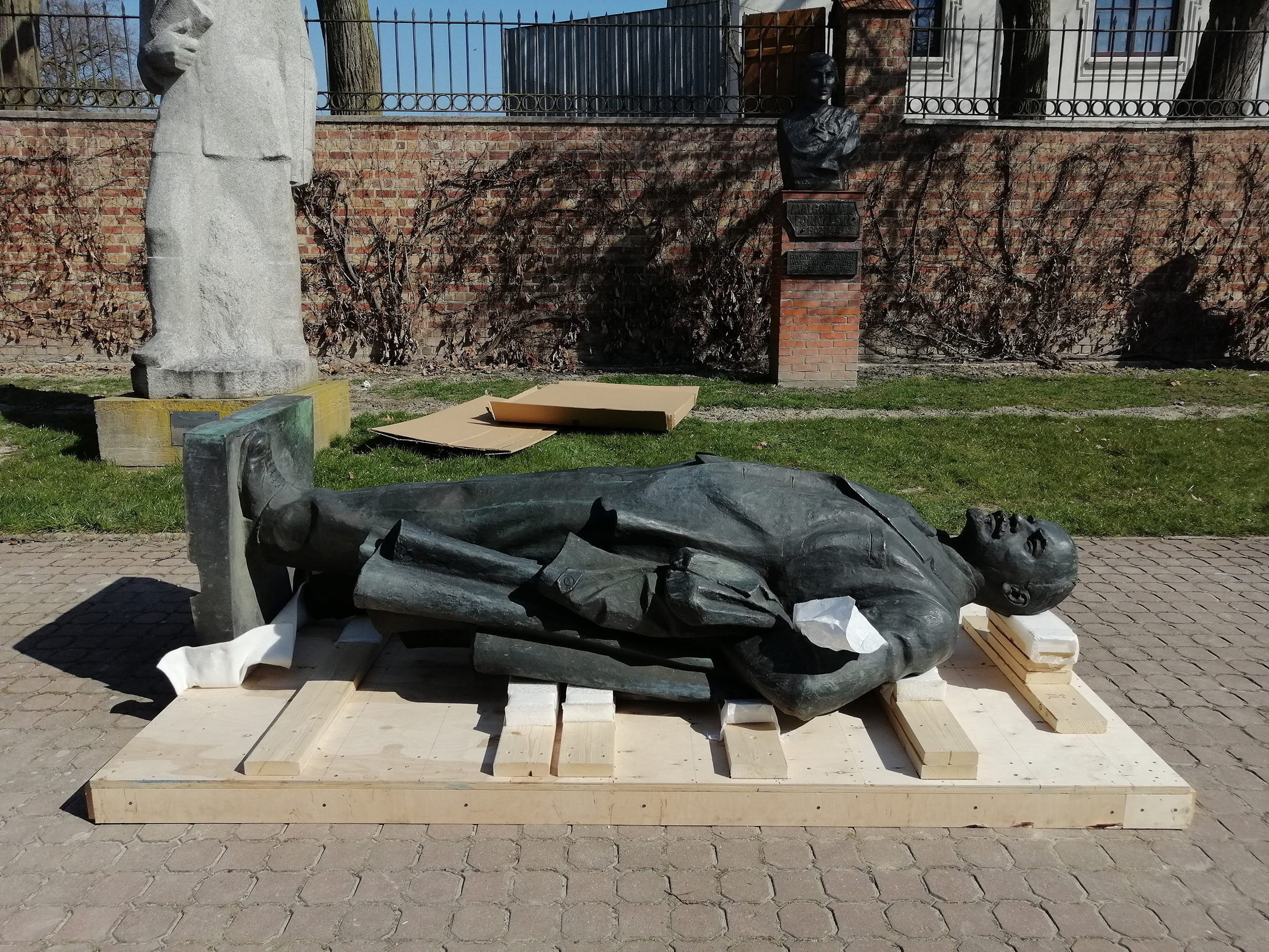 Pomnik Włodzimierza Lenina, postać całościowa. Rzeźba z brązu o wymiarach 260 x 120 x 75 cm ułożona poziomo na drewnianej podstawie.