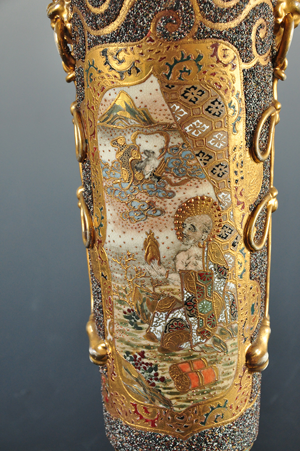 Na ceramicznym korpusie lampy naftowej bogato dekorowana złoceniami przestrzeń, w złotym ornamentem wydzielone pole wpisana dekoracja z kwiatami wiśni i piwonii oraz sójką