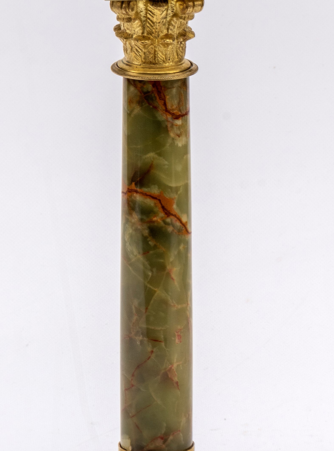Smukła kolumna zakończona głowicą złoconą wykonana z zielonego nefrytu z ciemnobrązowymi przebarwieniami.
