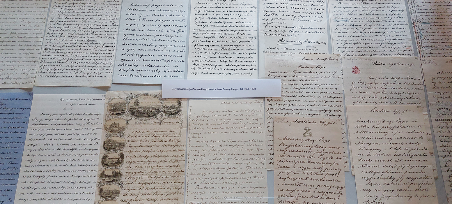 Fotografia przedstawiająca archiwalia zgromadzone przez Konstantego Zamoyskiego. W gablocie, ułożone jeden obok drugiego, listy Konstantego do ojca Jana Zamoyskiego, z lat 1861 – 1878.