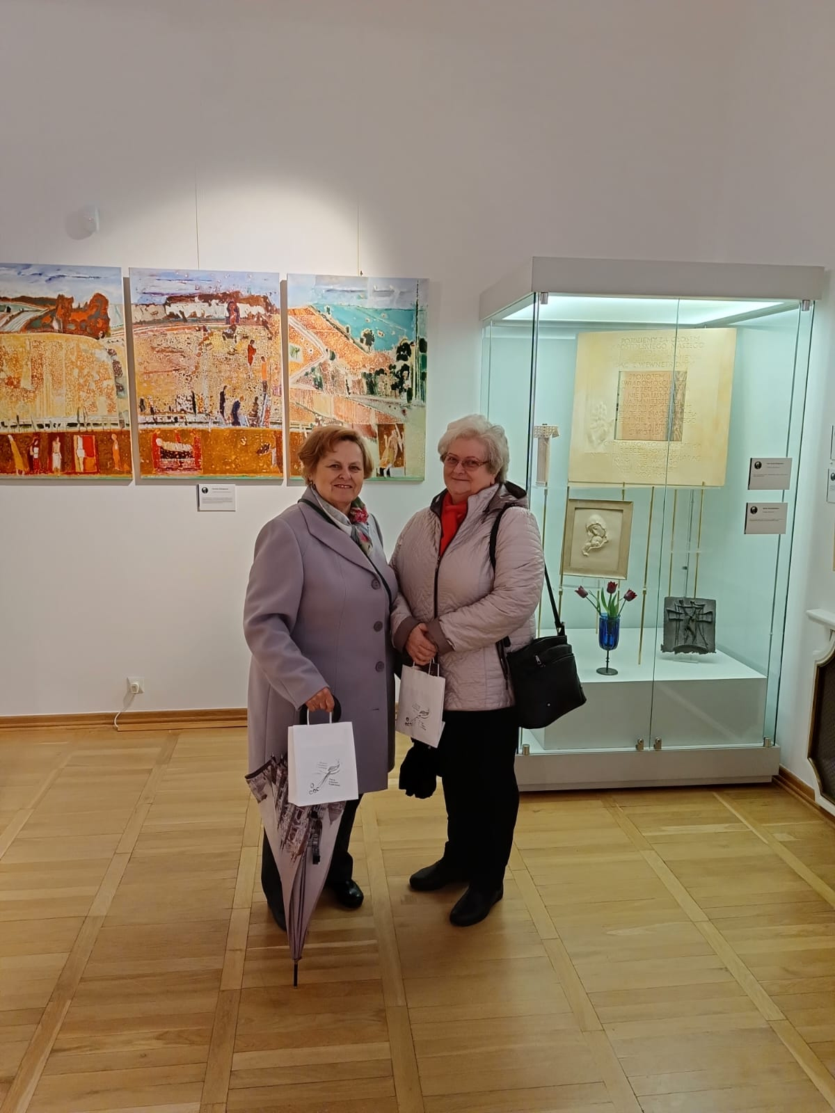 Dwie kobiety pozujące na tle wystawy „Wyszyński – Pater Patriae”