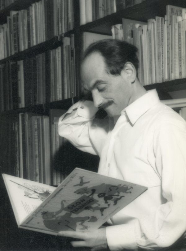Ignacy Witz z pierwszym wydaniem „Słonia Trąbalskiego”, ok. 1948; https://audycjekulturalne.pl/ignacy-witz/ Czarno – białe zdjęcie stojącego Ignacego Witza na tle szaf bibliotecznych, trzymającego w ręku egzemplarz książki Juliana Tuwima pt.: „Słoń Trąbalski”. Artysta ubrany w białą koszulę , w jednej ręce trzyma książkę, drugą trzyma za prawym uchem. Twarz dojrzałego mężczyzny, z wąsami, wysokim czołem oraz ciemnymi włosami zaczesanymi do tyłu.