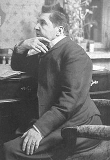 Maria Rodziewiczówna, 1911 r. , https://pl.wikipedia.org/wiki/Maria_Rodziewicz%C3%B3wna Zdjęcie przedstawia postać kobiety w średnim wieku, zwróconej w prawą stronę. Kobieta siedzi na fotelu, prawą ręka ma opartą o biurko, dłonią popiera swoją brodę natomiast jej lewa ręka jest opuszczona i oparta na nodze. Kobieta ma ciemne, krótkie włosy zaczesane na prawą stronę. Ubrana jest w ciemny żakiet zapinany na guziki, również ciemną, długą spódnicę oraz w białą koszulę z kołnierzykiem. W tle widać biurko, na którym leżą dokumenty.