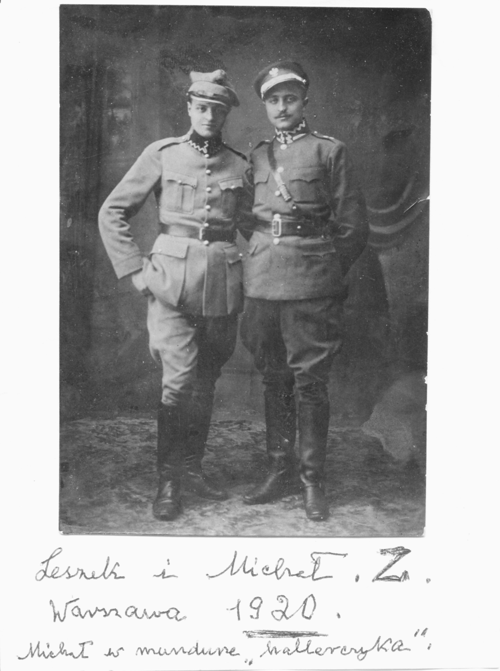 Czarno-biała fotografia. Aleksander i Michał Zamoyscy stojący obok siebie. Mężczyzna po prawej, starszy, z wąsikiem, ubrany w mundur Wojska Polskiego II RP. Kurtka zapinana na pięć guzików, z kołnierzem stojącym, wszytymi naramiennikami i dwiema kieszeniami na piersiach. Spodnie bryczesy wpuszczone w wysokie do kolan, skórzane buty. Na głowie rogatywka z umieszczonym na przodzie godłem. Mężczyzna po lewej ubrany w mundur hallerczyka. Kurtka zapinana na sześć guzików, z kołnierzem stojącym, wszytymi naramiennikami i dwiema kieszeniami na piersi oraz u dołu kurtki. Spodnie bryczesy wpuszczone w wysokie do kolan, skórzane buty. Na głowie rogatywka Poniżej napis: Leszek i Michał .Z. Warszawa 1920. Michał w mundurze hallerczyka.