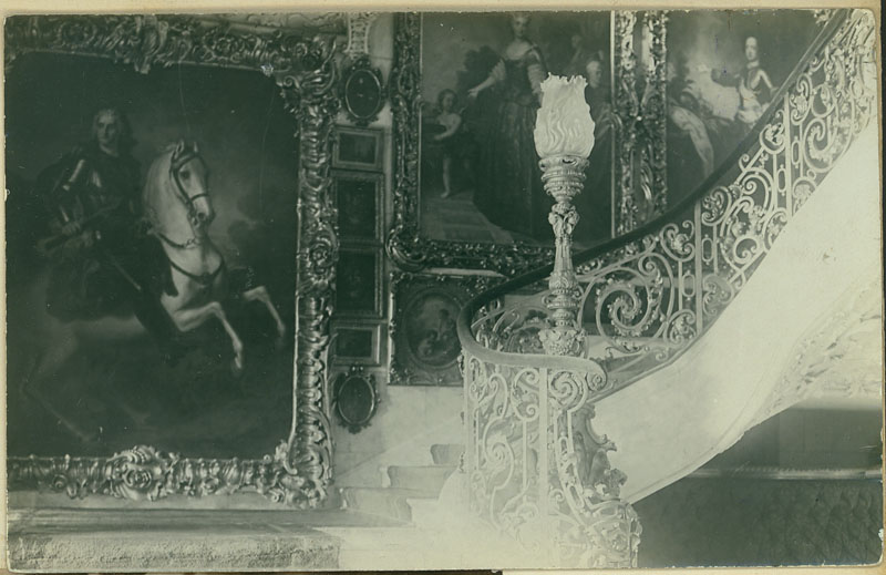 3. Klatka schodowa pałacu Zamoyskich w Kozłówce, Polska, 1926 – 1934; fotografia archiwalna; nr inw. MPK/F/57 Fotografia zabytkowa ukazująca fragment reprezentacyjnej Klatki schodowej pałacu kozłowieckiego. Marmurowe schody ozdobione są neorokokową balustradą firmy "Gostyńskiego" w Warszawie. Za balustradą dekoracyjna lampa naftowa. Na ścianach klatki obrazy różnych formatów. Na pierwszym planie widnieją trzy duże portrety: konny Augusta II Sasa, Marii Leszczyńskiej i Ludwika XV.