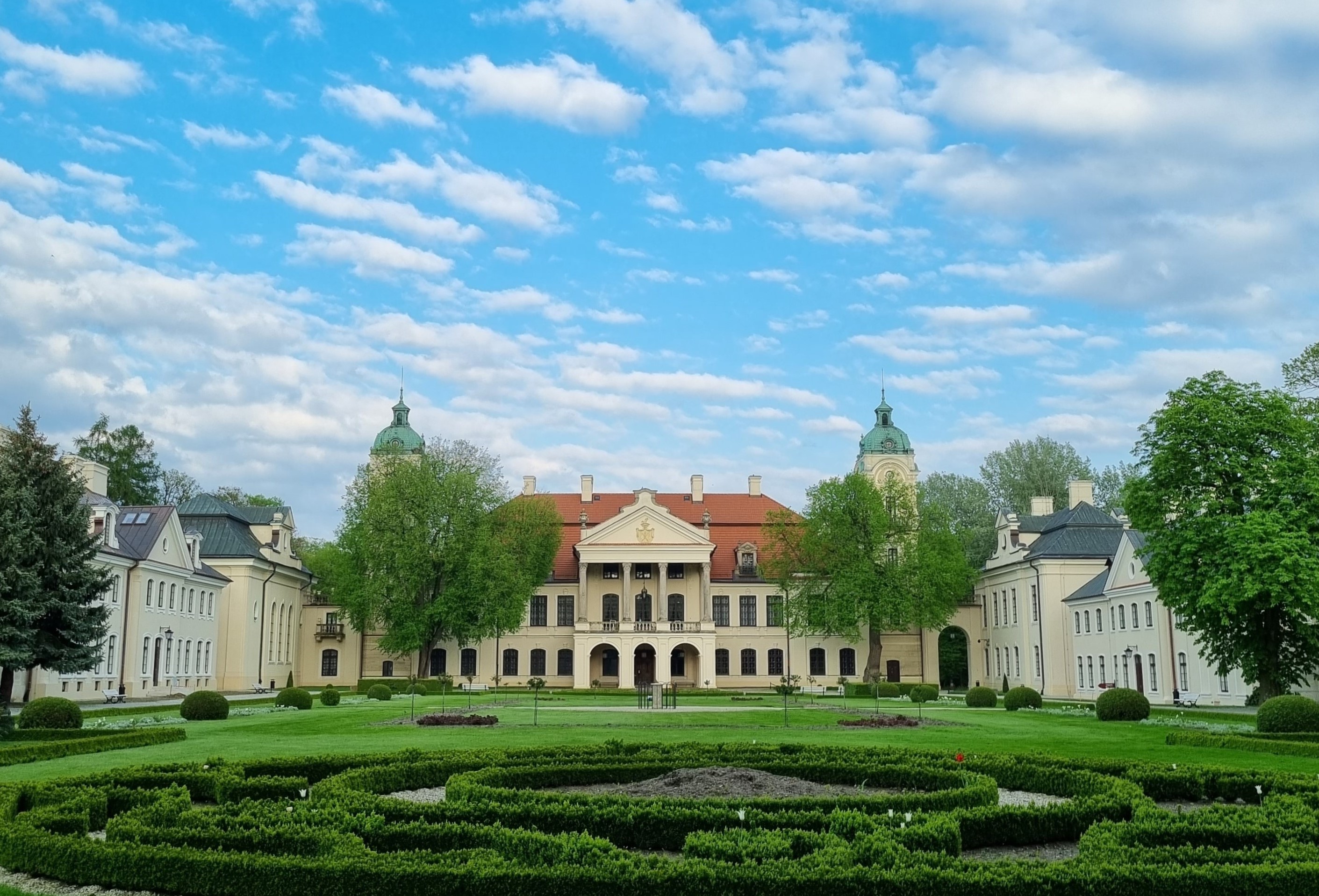 Widok dziedziniec założenia pałacowego w Kozłówce. Po środku pałac Zamoyskich, po bokach budynki oficyn.