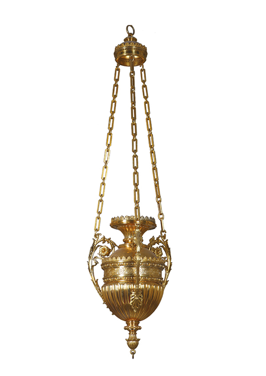 Lampa wieczna, Polska, Warszawa, Norblin i S-ka, początek XX wieku, mosiądz złocony, odlew, 202 x 232 cm, MPK/ZM/331 Na białym tle mosiężna lampa wieczna w kolorze złotym. Korpus lampy w kształcie owalnym. Do połowy korpusu ornament w formie wypukłych rozciągniętych łez, pośrodku pas dekoracji spiralnej z drobnymi wieżyczkami. Korpus w górnej część rozchylony kielichowo. Na korpusie trzy wygięte uchwyty z wici akantowej, do nich przymocowane łańcuchy z prostokątnych ogniw zebrane u góry podwieszeniem.
