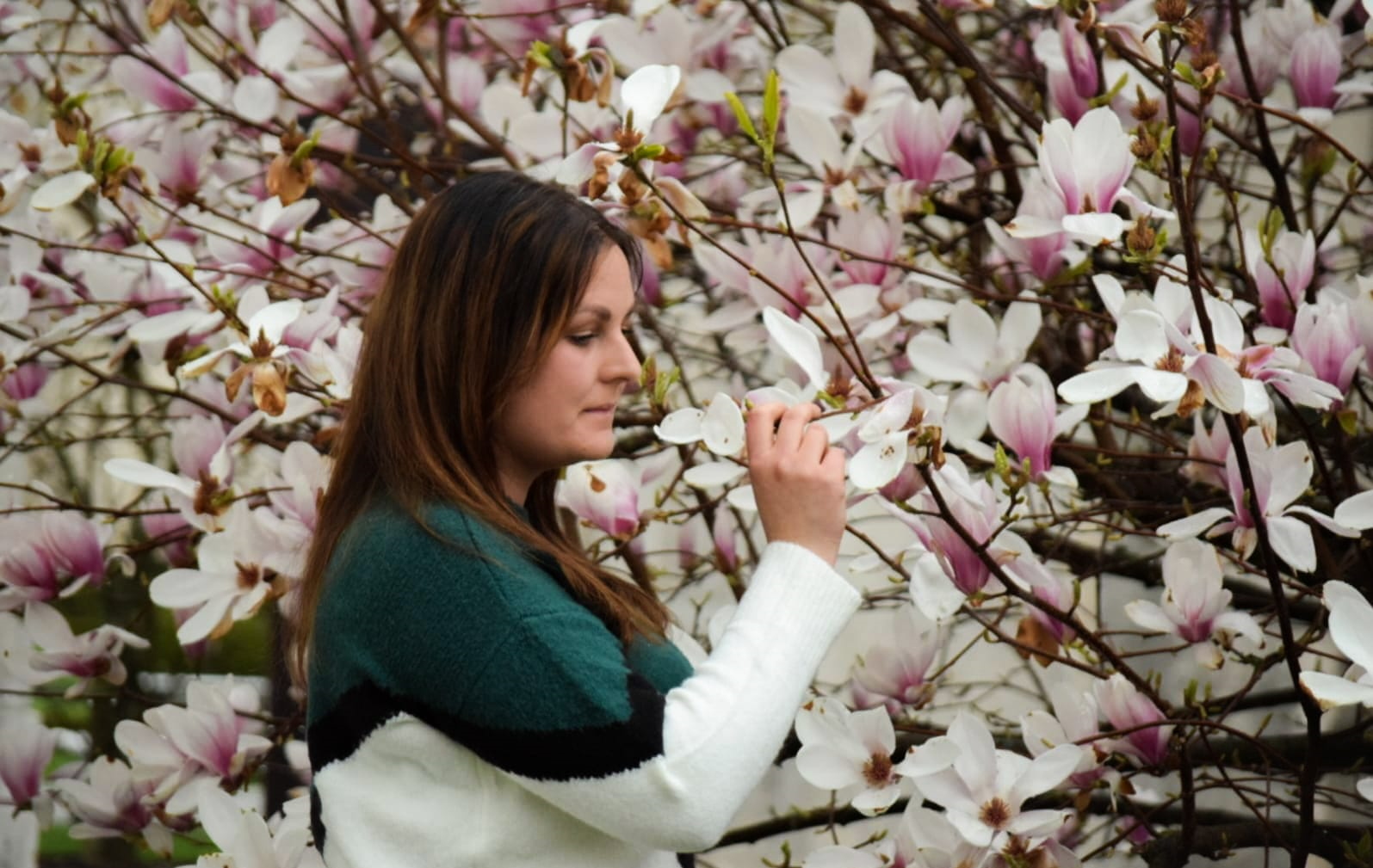 Młoda kobieta na tle kwitnącej magnolii
