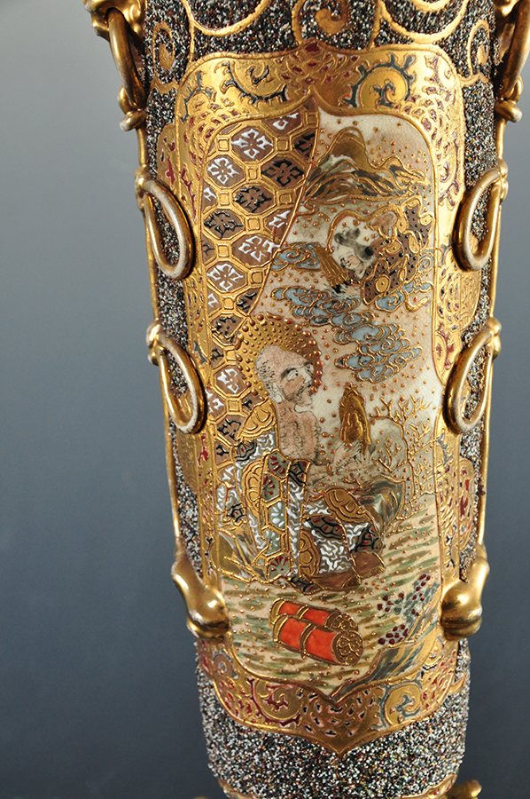 Dekoracja korpusu lampy, scena z japońskiej legendy o miłości Orihime i Hikoboshi; nr inw. MPK/CS/2050 Na ceramicznym korpusie lampy naftowej bogato dekorowana złoceniami przestrzeń. W polu scena ukazująca klęczącego mężczyznę trzymającego złoty przedmiot w dłoni, nad nim z chmur wyłania się pochylona w jego kierunku w popiersiu postać kobieca.