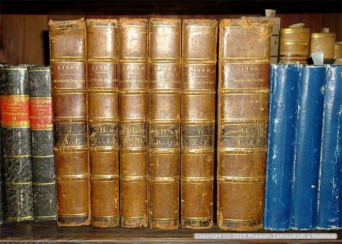 8. Pierwsze wydanie „Słownika języka polskiego” w kozłowieckiej bibliotece zabytkowej Fotografia przedstawia pierwsze wydanie „Słownika języka polskiego” z kozłowieckiej biblioteki zabytkowej. Sześć tomów stoi wśród innych książek, na półce szafy bibliotecznej. Książki są oprawione w brązową skórę. Na grzbiecie każdego tomu umieszczony jest tłoczony, złocony napis wersalikami: LINDE, SŁOWNIK POLSKI