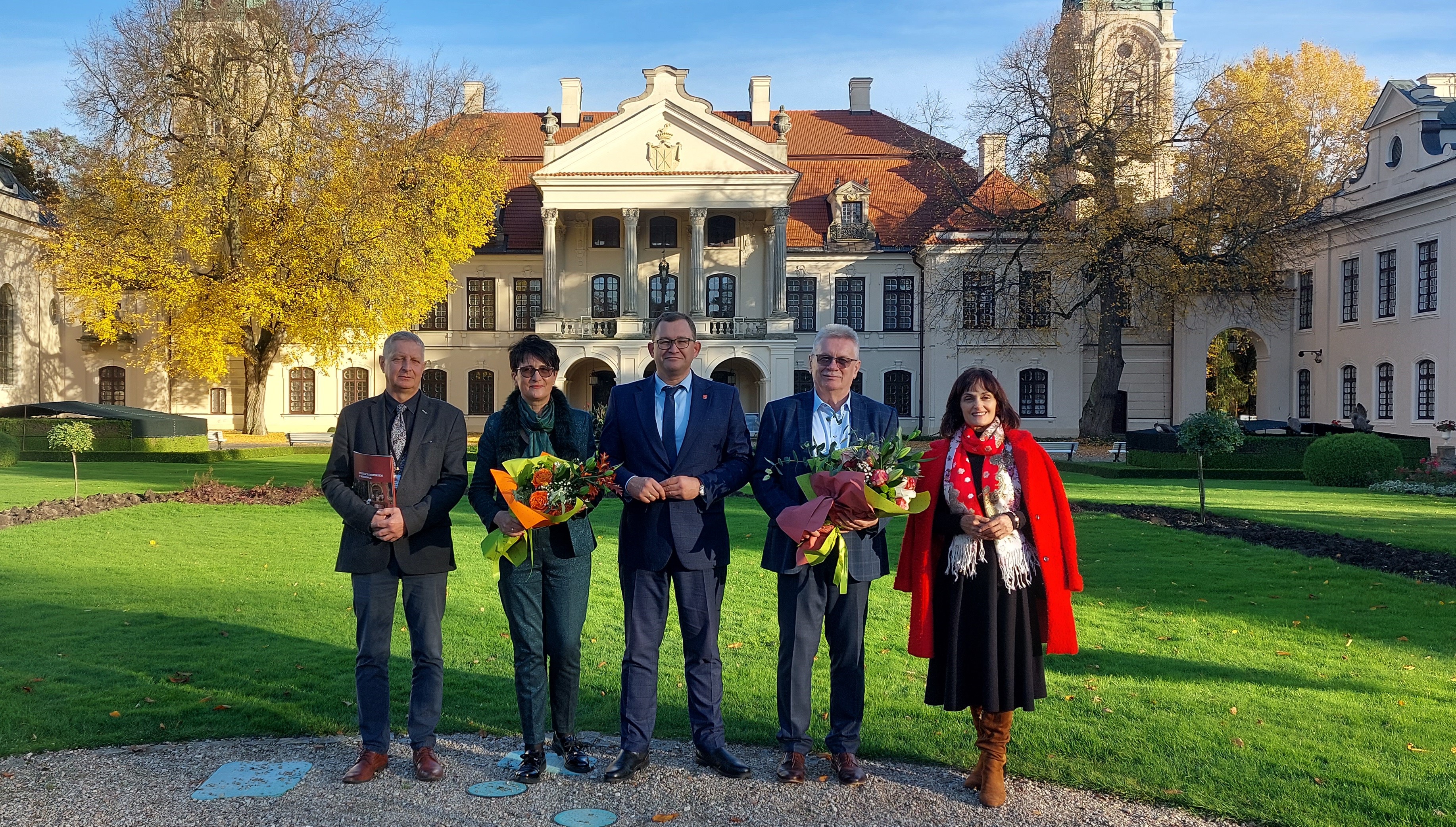 Od lewej: Sławomir Grzechnik, zastępca dyrektora Muzeum Zamoyskich w Kozłówce; Bożena Ćwiek, dyrektor Muzeum Zamoyskich w Kozłówce; Bartłomiej Bałaban, Członek Zarządu Województwa Lubelskiego; Jerzy Dębski, p.o. dyrektora Muzeum Zamoyskich w Kozłówce, Elżbieta Katarzyna Kędzierska, dyrektor Departamentu Kultury, Edukacji i Dziedzictwa Narodowego w Urzędzie Marszałkowskim  Województwa Lubelskiego.

Fotografia przedstawiająca grupę pięciu osób, dwie kobiety i trzech mężczyzn. W tle okazały piętrowy pałac z wysuniętym portykiem, pokryty dwuspadowym dachem z czerwoną dachówką.