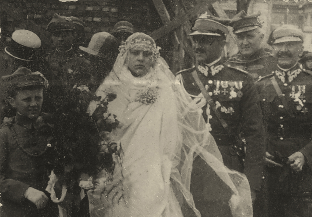 Ślub Aleksandra Leszka Zamoyskiego i Jadwigi Belina Brzozowskiej, Częstochowa, Jasna Góra, 3 maja 1925; z Archiwum Rodziny Belina Brzozowskich Czarno-biała, archiwalna fotografia ślubna przedstawiająca Jadwigę i Aleksandra Leszka Zamoyskich w otoczeniu gości. Na pierwszym planie, Panna Młoda ubrana w białą suknię i długi otulający twarz i sylwetkę welon. Obok niej po prawej, Pan Młody w mundurze galowym Wojska Polskiego, po lewej chłopiec w mundurze „Sokoła”? trzymający w dłoni bukiet, prawdopodobnie czerwonych, róż.
